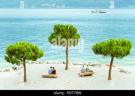 Deux couples d'âges différents assis sur la plage de Limone sul Garda, Italie. Banque D'Images