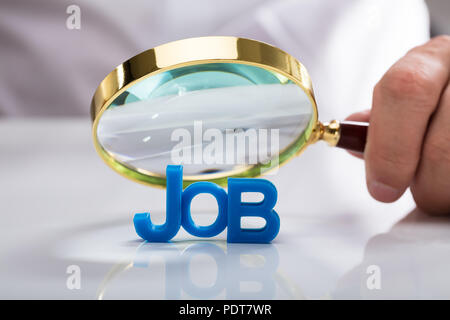 Businessman's hand holding loupe sur emploi mot bleu Banque D'Images