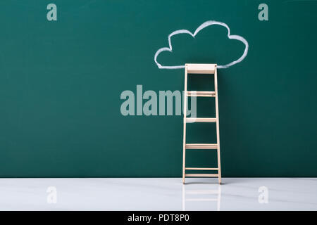 Échelle en bois s'appuyant sur tableau noir avec une craie verte appelée Cloud Banque D'Images