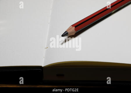 Crayon affûté sur un ordinateur portable blanc. White pages vides d'un cahier avec un crayon de rédaction. Fournitures scolaires. Banque D'Images