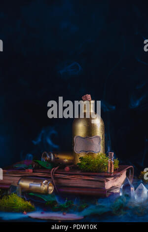 Dans un flacon de potion d'or toujours la vie avec un équipement occulte sur un fond sombre. Sorcière ou un milieu de travail de l'assistant de copie avec l'espace. Banque D'Images