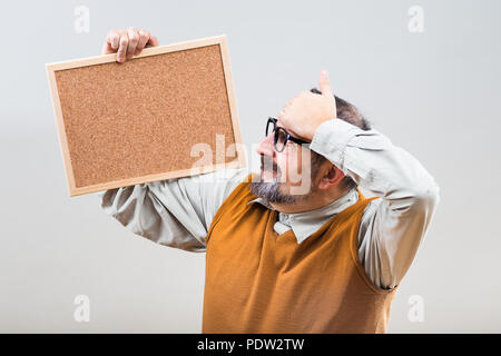 Businessman nerdy est en panique parce que d'une chose tout en maintenant vide panneau de liège. Banque D'Images