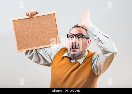 Businessman nerdy est en panique parce que d'une chose tout en maintenant vide panneau de liège. Banque D'Images