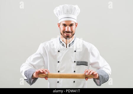 Portrait de chef holding Rolling pin sur fond gris. Banque D'Images