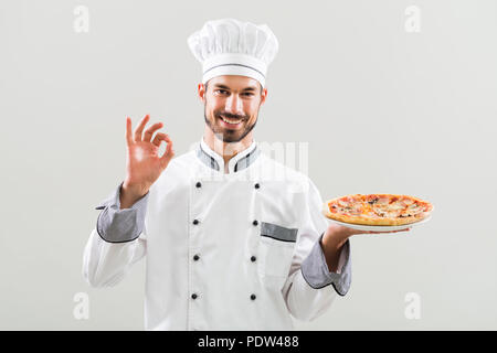 Chef holding pizza et montrant ok signe. Banque D'Images