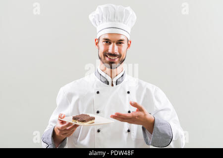 Pâtissier est montrant les tranches de gâteau sur fond gris. Banque D'Images