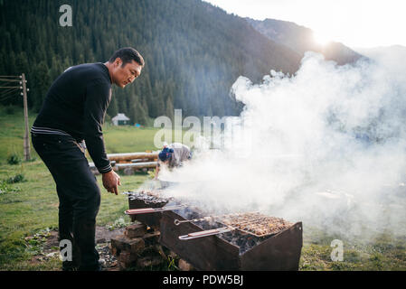 Dans la famille Kirghizistan cuire le dîner à l'extérieur sur feu de bois Banque D'Images