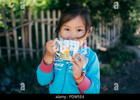 Portrait d'une petite fille avec une tasse de thé au Kirghizstan Banque D'Images