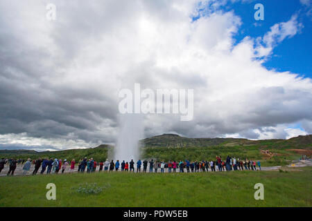 Les foules se rassemblent pour surveiller un petit geyser éclater à une zone thermique dans la ville de Strokkur Geysir, Islande. Banque D'Images