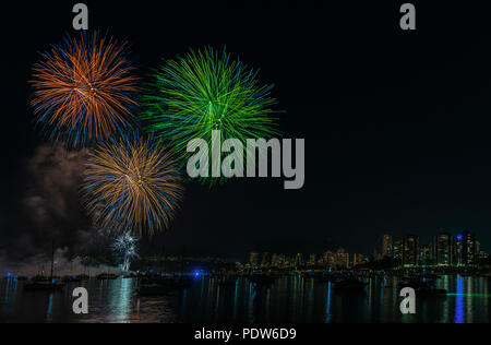 Des flashes de couleur nuit d'artifice au-dessus de l'océan avec des yachts et bateaux près d'une grande ville moderne avec des immeubles de grande hauteur Banque D'Images
