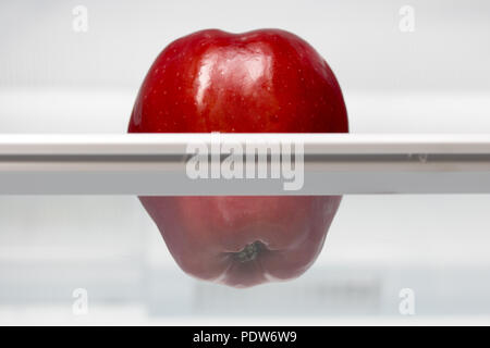 Une pomme rouge sur une étagère dans un réfrigérateur. Une pomme fraîche dans un réfrigérateur. Fruits est un refroidissement dans le stockage. Banque D'Images