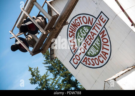 Résumé de l'image inclinée Washington Egg & Poultry Association Co-Operative bâtiment dans Winlock, Washington, avec les signaux de chemin de fer en face de lui. Banque D'Images