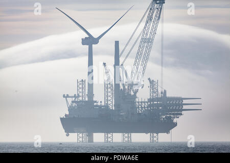 Seajacks travaillant sur le Scylla Extension Walney éoliennes en mer dans des conditions brumeuses. Couverture nuageuse inhabituelle de formations peuvent se voir dans la distance Banque D'Images