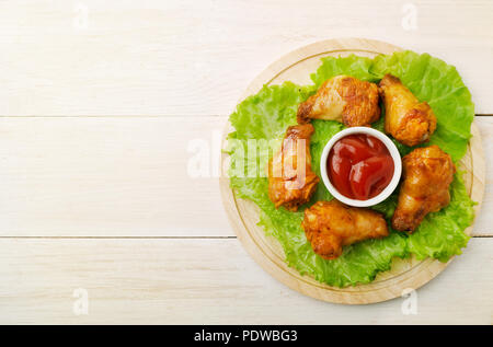 Ailes frit avec du ketchup sur un fond en bois et la place pour le texte Banque D'Images
