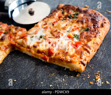 Tranches de carrés de style italien délicieux pizza Margarita à bord avec cutter Banque D'Images