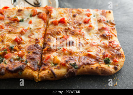 Tranches de carrés de style italien délicieux pizza Margarita à bord avec cutter Banque D'Images