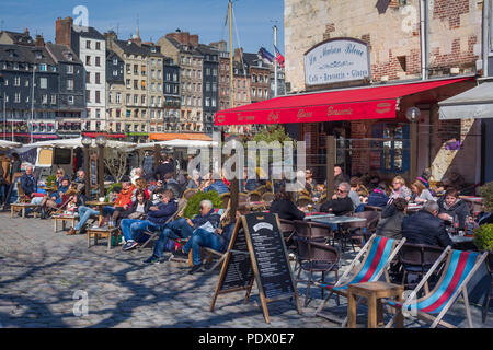 Assis dans le soleil d'hiver dans un café par le vieux port, Vieux Bassin, à Honfleur, Normandie, France Banque D'Images