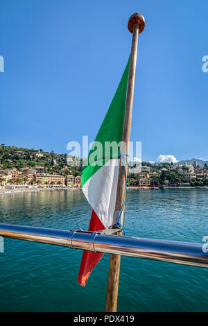 Drapeau italien à l'arrière d'un bateau avec la côte méditerranéenne en arrière-plan - pour une utilisation en arrière-plan Banque D'Images