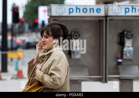 Extra film femme habillée dans le style des années 60, en face de American Vintage Phone Booth pour sa prochaine scène, tourné à Liverpool UK, basée sur Washington DC USA Banque D'Images