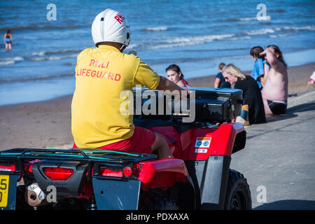 Sauveteur RNLI sur un quad bike patrouiller plage centrale, Prestatyn, Nord du Pays de Galles, Royaume-Uni, pendant la canicule de l'été 2018. Banque D'Images