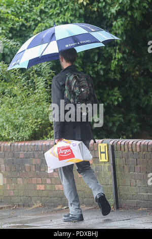 Londres. UK 10 Aug 2018 - Un homme d'hébergement de la pluie sous un parapluie dans le nord de Londres. D'après le Met Office le temps incertain est susceptible de se poursuivre au cours des prochains jours. Credit : Dinendra Haria/Alamy Live News Banque D'Images