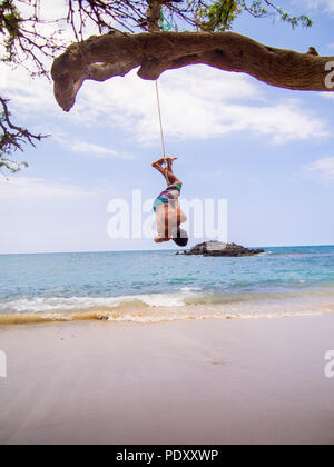L'homme se balançant à l'envers sur la corde à Ocean Beach, Florida, USA Banque D'Images