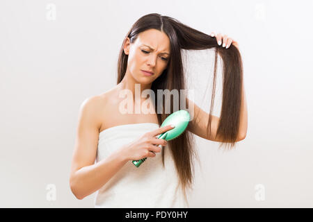 Image de femme en colère brosser ses cheveux sur fond gris. Banque D'Images