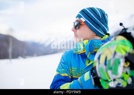 Portrait de l'Homme à lunettes avec snowboard à main sur fond de montagnes neige Banque D'Images