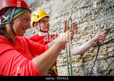 Photo de l'homme et la femme en rouge T-shirt avec corde de sécurité sur la montagne de l'arrière-plan Banque D'Images