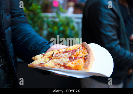 Deux gros morceaux de pizza dans les mains d'un homme. Le déjeuner dans la rue. L'alimentation de rue dans la ville de l'Europe. Espace libre pour le texte. Banque D'Images