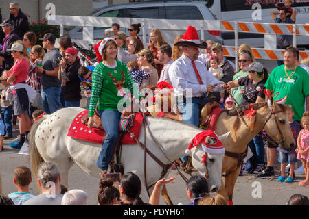 Deux cavaliers avec chapeaux de Noël à Georgetown, Texas, défilé de Noël annuel avec des foules regardant. Banque D'Images