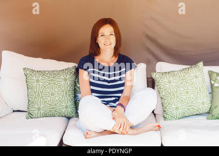 Portrait of smiling middle aged white Caucasian belle jeune femme aux longs cheveux rouges bob, en t-shirt rayé bleu et blanc pantalon en coton. Si Femme Banque D'Images