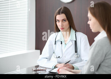 Le médecin et le patient à l'hôpital. Médecin de la mise à niveau de traitement historique records en parlant avec jeune femme. Santé et médecine concept. Banque D'Images