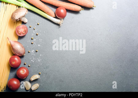 Vue du haut vers le bas sur la cuisine des ingrédients comme des nouilles, l'ail, l'oignon, les tomates, champignons ou d'épices sur ardoise, With Copy Space Banque D'Images