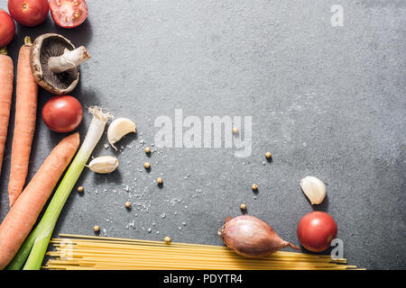 Vue du haut vers le bas sur la cuisine des ingrédients comme les nouilles, carottes, oignons, tomates, poireau ou d'épices sur ardoise, With Copy Space Banque D'Images