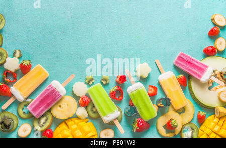 Frontière de diverses couleurs ice cream les sucettes glacées avec des tranches de fruits et de baies ingrédients sur fond bleu clair, haut Vue, télévision lay. Frozen Banque D'Images
