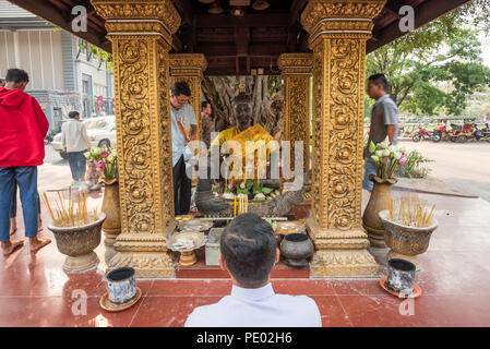 Fidèles cambodgiens priant devant Maître King statue situé sous un arbre et au milieu de la route, Siem Reap, Cambodge Banque D'Images