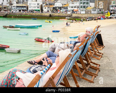 ST Ives, Angleterre - le 19 juin : les personnes plus âgées, en vacances, assis dans une rangée de chaises longues dans le port de St Ives, Cornwall. À St Ives, en Angleterre. Le 19 juin Banque D'Images