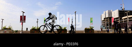 Vue panoramique sur les piétons et cyclistes en silhouette le long de Stratford à pied, Queen Elizabeth Olympic Park, Stratford, London, England Banque D'Images