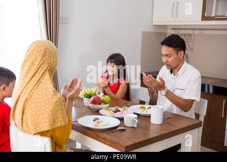 Happy asian famille musulmane prier avant d'avoir un repas ensemble à la maison Banque D'Images