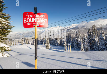 Traces dans la neige à côté d'un signe des limites de la zone de ski. Banque D'Images