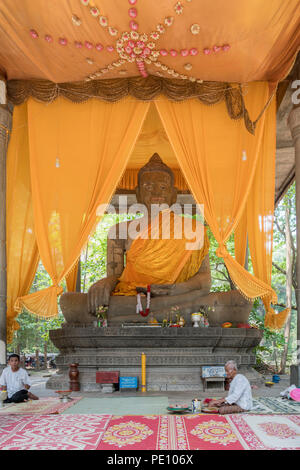 Les fidèles priant devant une grande statue de Bouddha assis jambes croisées, Wat Preah Ngok (ou Preah Ngoc), Angkor, Krong Siem Reap, Cambodge Banque D'Images