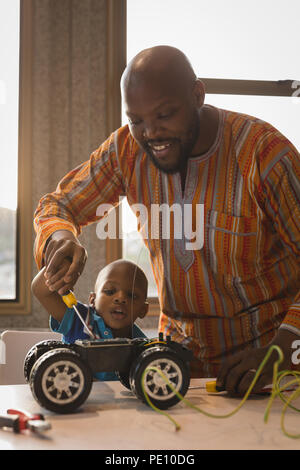 Père et fils jouant avec la voiture électrique Banque D'Images