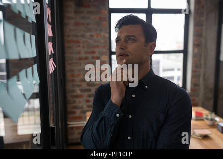 Businessman looking at sticky notes in office Banque D'Images