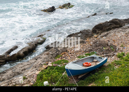 Petite barque est situé sur les rochers sur la côte d'Alghero Banque D'Images