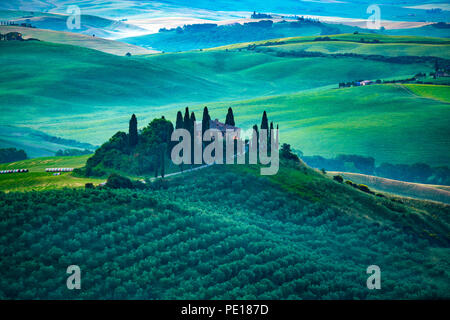 Vue sur un magnifique paysage de collines tôt le matin avec la ferme les arbres de cyprès et bottes de foin à la Toscane en Italie Banque D'Images