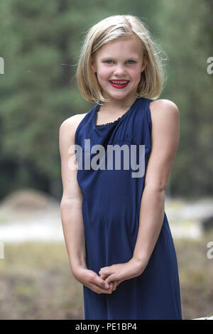 Jolie jeune femme blonde preteen, sourire, rire, à l'extérieur, 3/4 profil, robe bleue, Moody, modèle publié. Banque D'Images