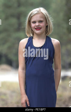 Jolie jeune femme blonde, des photos de mode, les préadolescentes. Smiling at camera, à l'extérieur, 3/4 profil, robe bleue, Moody, modèle publié. Banque D'Images