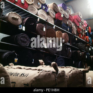 Années 1960, de gros rouleaux de Harris Tweed fini empilés sur des étagères dans un entrepôt, Highlands, Ecosse, Royaume-Uni. Banque D'Images