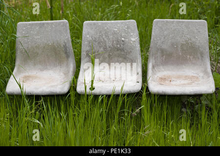 Un trio de vieilles chaises en plastique moulé abandonnés dans un champ sur la commune de Varen, Tarn et Garonne, l'Occitanie, la France au printemps Banque D'Images